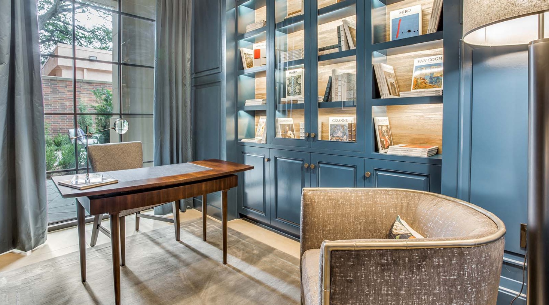 A home den has floor-to-ceiling windows and a built-in library